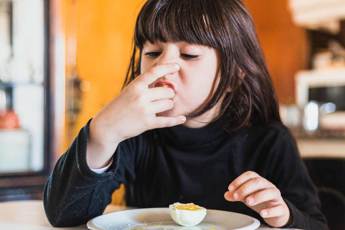 Seorang anak sedang makan telur 